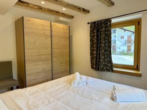a bedroom with a white bed and a window at Alpine Grace in Falcade