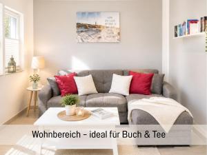 a living room with a gray couch with red pillows at Schwedenglück - Wald-Auszeit für 2 in Dahlen