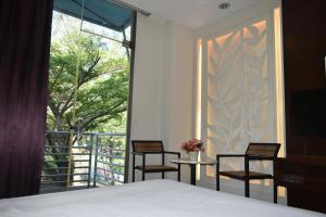 a bedroom with two chairs and a bed and a window at D'Wharf Hotel PD Waterfront in Kampong Bangsal Kapor