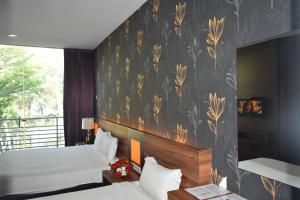 a bedroom with two beds and a wall with a floral wallpaper at D'Wharf Hotel PD Waterfront in Kampong Bangsal Kapor