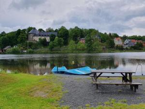 a picnic table next to a lake with a boat at Ferienwohnung Wagner in Stiege