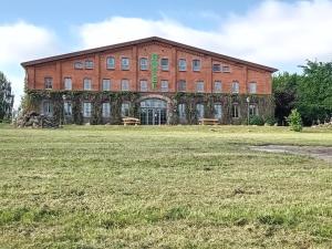 a large brick building with a field in front of it at Scheunen-Domizil in Bollewick