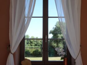 a window with white curtains and a view of a yard at Scheunen-Domizil in Bollewick