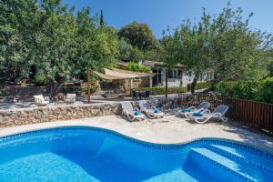 a swimming pool with chairs and a table and a house at Can Miquel, villa in Pollensa in Pollença