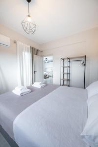 a white bedroom with two beds and a window at DION APARTMENTS in Paleros