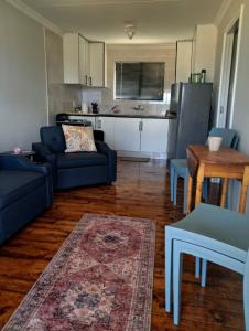 a living room with two blue couches and a kitchen at Herdman's Rest Farmstay in Lady Grey