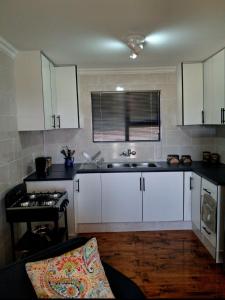 a kitchen with white cabinets and a sink and a stove at Herdman's Rest Farmstay in Lady Grey