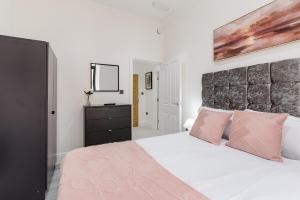 a bedroom with a large white bed with pink pillows at Modern City Centre Ground Floor - Apt 6 in Bradford