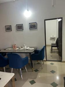 a dining room with a table and blue chairs at Camellia The Bungalow in Dibrugarh
