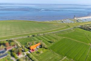 an aerial view of a house in a field next to the ocean at Ferienwohnung Landleben am Meer in Bensersiel