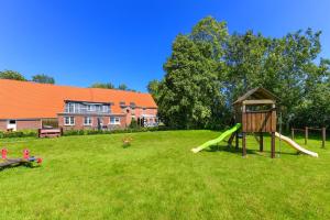 a playground with a slide in a yard with a house at Ferienwohnung Landleben am Meer in Bensersiel