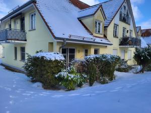 a house with snow covered bushes in front of it at An der Schmiedestraße Strandläufer in Wustrow +17 photos