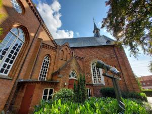 a large brick church with a camera in front of it at Ferienwohnung am Kirchplatz 25561 in Weener