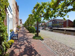 a tree on a brick sidewalk next to a street at Ferienwohnung am Kirchplatz 25561 in Weener