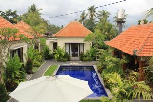 an umbrella in front of a house with a pool at Uma Budhas in Ubud