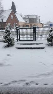 a snow covered yard with a fence and trees at FeWo Hasen Suite in Worpswede