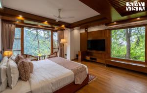 a bedroom with a bed and a tv and windows at Simla Manor by VEO - Part of StayVista in Shimla +78 photos