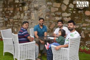 a group of men sitting around a table with a child at Simla Manor by VEO - Part of StayVista in Shimla
