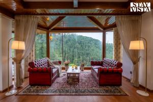 a living room with two couches and a table at Simla Manor by VEO - Part of StayVista in Shimla