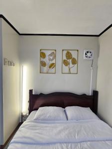 a bedroom with a bed with two pictures on the wall at Raed Homestay by ASH in Biñan