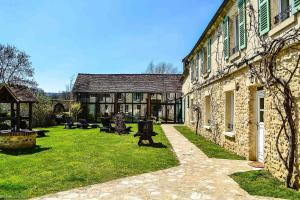 a large stone building with a grass yard in front of it at Le Clos des Vignes in Neuville-Bosc