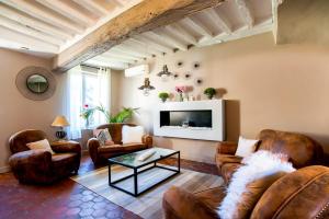 een woonkamer met lederen meubels en een televisie bij Le Clos des Vignes in Neuville-Bosc