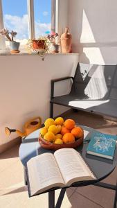 a table with a bowl of oranges and an open book at Casa Manzoni- Appartamento con terrazzo in centro in Mussomeli +39 photos