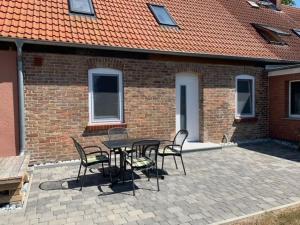 a patio with a table and chairs in front of a brick building at Ferienwohnungen Schaprode Udars in Udars