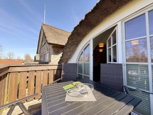 a table and chairs on a deck on a house at Haus an der Düne Whg 10 in Lobbe