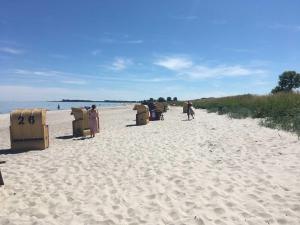 a group of people standing on a sandy beach at Reetdachhaus De Ole Kaat in Niesgrau +33 photos