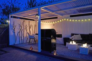 a gazebo with a couch and a television and candles at Reetdachhaus De Ole Kaat in Niesgrau