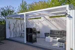 a white pergola with a couch and a table at Reetdachhaus De Ole Kaat in Niesgrau