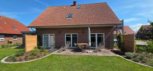 a house with a table and chairs in the yard at Nr 200 - Ferienwohnung Süderriff in Neuharlingersiel