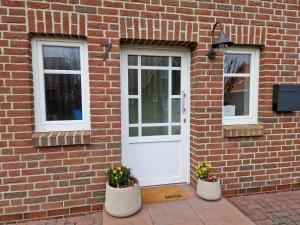 a brick building with a white door and two windows at Nr 200 - Ferienwohnung Süderriff in Neuharlingersiel +18 photos