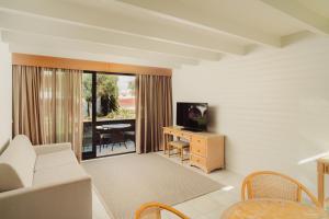a living room with a couch and a tv and a table at Topazio Vibe Beach Hotel & Apartments - Adults Friendly in Albufeira