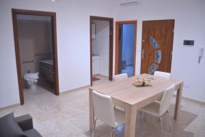 comedor con mesa de madera y sillas blancas en Appartamento Via Lata, en Brindisi