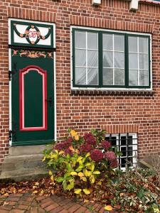 eine grüne Tür und ein grünes Fenster an einem Backsteingebäude in der Unterkunft Altländer Obsthof in Hollern-Twielenfleth