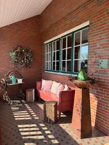 eine Terrasse mit einem roten Sofa und einer Backsteinmauer in der Unterkunft Altländer Obsthof in Hollern-Twielenfleth