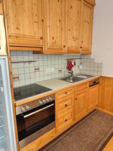 a kitchen with wooden cabinets and a sink and a stove at Appartements Bel Monte - Kärnten Card im Sommer inklusive in Bad Kleinkirchheim