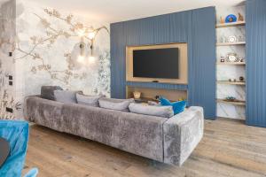 a living room with a gray couch and a tv at Mirabello Private Pool Apartment in Bardolino