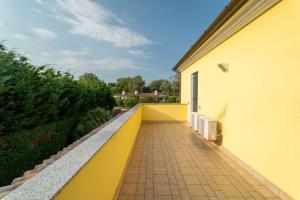 a balcony with a yellow wall and a sidewalk at Scirocco in Isola Albarella