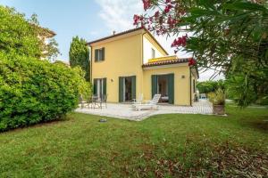 a yellow house with a patio in a yard at Scirocco in Isola Albarella +37 photos