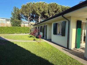 a house with a grass yard next to a building at Adria in Isola Albarella