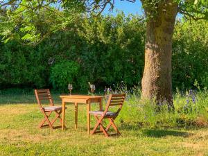 a wooden table with two chairs and two glasses of wine at Ferienwohnungen Klein Kapelle in Gingst