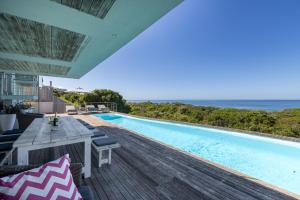 an outdoor deck with a swimming pool and the ocean at Seascape in Plettenberg Bay