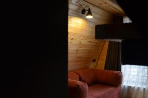 a couch in a room with a wooden wall at MM's Cottage in Kazbegi