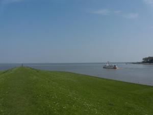a boat in the water near a grassy hill at Ferienwohnung Abbey Road in Varel