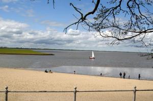a sail boat in the water with people on the beach at Ferienwohnung Abbey Road in Varel