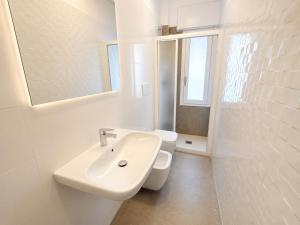 a white bathroom with a sink and a toilet at RESIDENCE PACE - Agenzia Cocal in Caorle