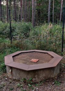 a concrete circle in the dirt in front of a fence at Wasserturm Spreewitz in Spreewitz